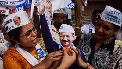 AAP supporters offering sweets (laddu) to party supremo and Delhi CM Arvind Kejriwal cut-out after crossing majority mark.&nbsp; (Bachchan Kumar / HT )