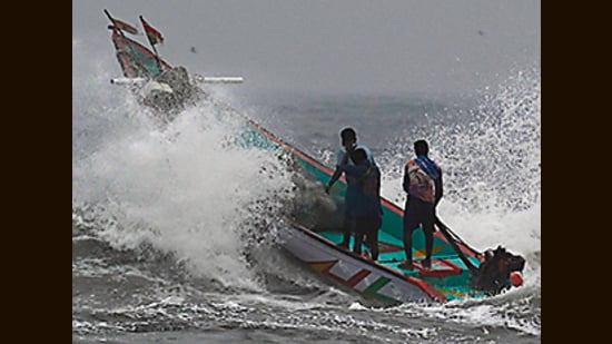 Fishermen manoeuvre their boat through waves at Pattinapakkam beach in Chennai, ahead of Cyclone Mandous forecasted landfall in north Tamil Nadu-south Andhra Pradesh coasts. (AFP)