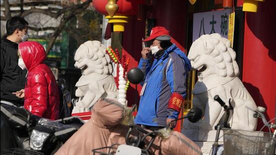 A pandemic volunteer adjusts his mask near stone lions outside a supermarket in Beijing, on Wednesday. In a sharp reversal, China has announced a series of measures rolling back some of the most draconian anti-Covid-19 restrictions. (AP) A pandemic volunteer adjusts his mask near stone lions outside a supermarket in Beijing, on Wednesday. In a sharp reversal, China has announced a series of measures rolling back some of the most draconian anti-Covid-19 restrictions. (AP)