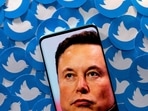 An image of Elon Musk is seen on a smartphone placed on printed Twitter logos in this picture illustration.