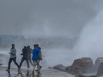 People stand near a stone ledge amid gusty winds as dark clouds loom over the Kasimedu fishing harbour in Chennai on Thursday.(AFP) People stand near a stone ledge amid gusty winds as dark clouds loom over the Kasimedu fishing harbour in Chennai on Thursday.(AFP)