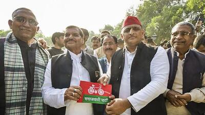Samajwadi Party chief Akhilesh Yadav presents the party flag to his uncle Shivpal Yadav whose Pragatisheel Samajwadi Party-Lohia merged with the SP, in Etawah on Thursday. (PTI PHOTO)