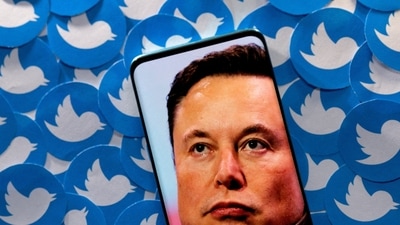 An image of Elon Musk is seen on a smartphone placed on printed Twitter logos in this picture illustration. (REUTERS)