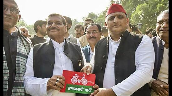 Samajwadi Party chief Akhilesh Yadav presents party flag to his uncle and Pragatisheel Samajwadi Party leader Shivpal Yadav, in Etawah, Thursday. (PTI Photo)