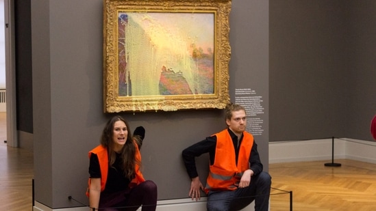 Last Generation activists seen glued underneath the painting "Les Meules" by French artist Claude Monet after throwing mashed potatoes on the artwork in the Barberini museum in Potsdam, Germany on October 23. "How do you feel when you see something beautiful and priceless apparently being destroyed before your eyes?" asked one of the protesters from Just Stop Oil after gluing themselves to the glass protecting a Vermeer painting in the Netherlands. "Do you feel outraged? Good. Where is that feeling when you see the planet being destroyed?" (Last Generation / AFP)