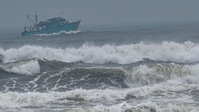 A fishing trawler sails amid high tide as dark clouds loom over the Kasimedu fishing harbour ahead of Cyclone Mandous forecasted landfall in north Tamil Nadu-south Andhra Pradesh coasts.&nbsp; (AFP)