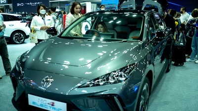 People are seen next to the MG 4 EV car at the 39 Thailand International Motor Expo, in Bangkok, Thailand, November 30, 2022. REUTERS/Athit Perawongmetha