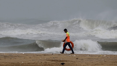A lifegaurd walks along the sea-shore as waves crash onto the shore ahead of the landfall of cyclonic storm Mandous, in Chennai, on Friday.&nbsp; (PTI)