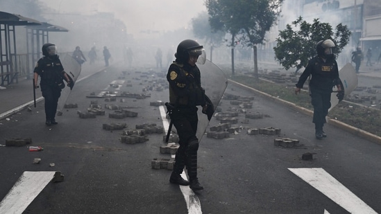 Members of the police seen after clashes with supporters of Pedro Castillo in the outskirts of the Lima Prefecture, where the leader is under detention, in Lima, on December 7. (Ernesto Benavides / AFP)
