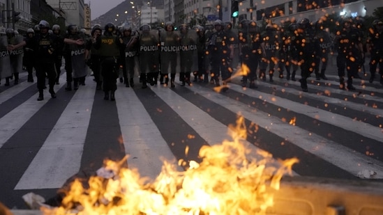 Police approach a burning barricade set up by supporters of ousted Castillo during clashes with police, in Lima, Peru, on Thursday, December 8. Even with unrest on a high, analysts predict a tough road for the new president- a 60-year-old lawyer and political neophyte. Jorge Aragón, a political science professor at Peru's Pontifical Catholic University told AP that a Boluarte government “is going to be very complicated, if not impossible.” (Fernando Vergara / AP)