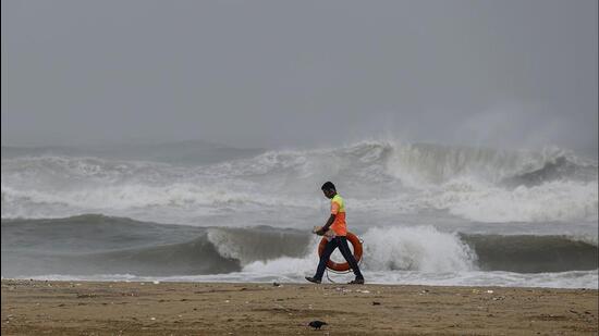 A lifegaurd walks along the sea-shore as waves crash onto the shore ahead of the landfall of cyclonic storm Mandous, in Chennai. (PTI)
