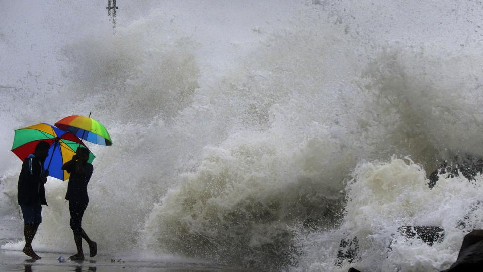 People hold their umbrella as they walk on an embankment against gusty winds and high waves in Chennai on Friday (AP) People hold their umbrella as they walk on an embankment against gusty winds and high waves in Chennai on Friday (AP)