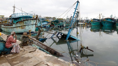 Chennai fisherman looking at damaged boats which was caused by the rainfall due to Cyclone. (PTI) Chennai fisherman looking at damaged boats which was caused by the rainfall due to Cyclone. (PTI)