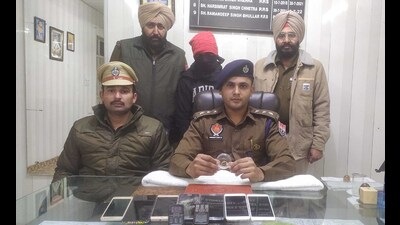 The accused (face covered) and valuables recovered from him in police custody. (HT Photo)