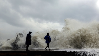 Cyclone Mandous: People stand on Kasimedu fishing harbour being hit by the high tides due to the strong winds triggered by Cyclone Mandous, in Chennai on Friday. (ANI) Cyclone Mandous: People stand on Kasimedu fishing harbour being hit by the high tides due to the strong winds triggered by Cyclone Mandous, in Chennai on Friday. (ANI)
