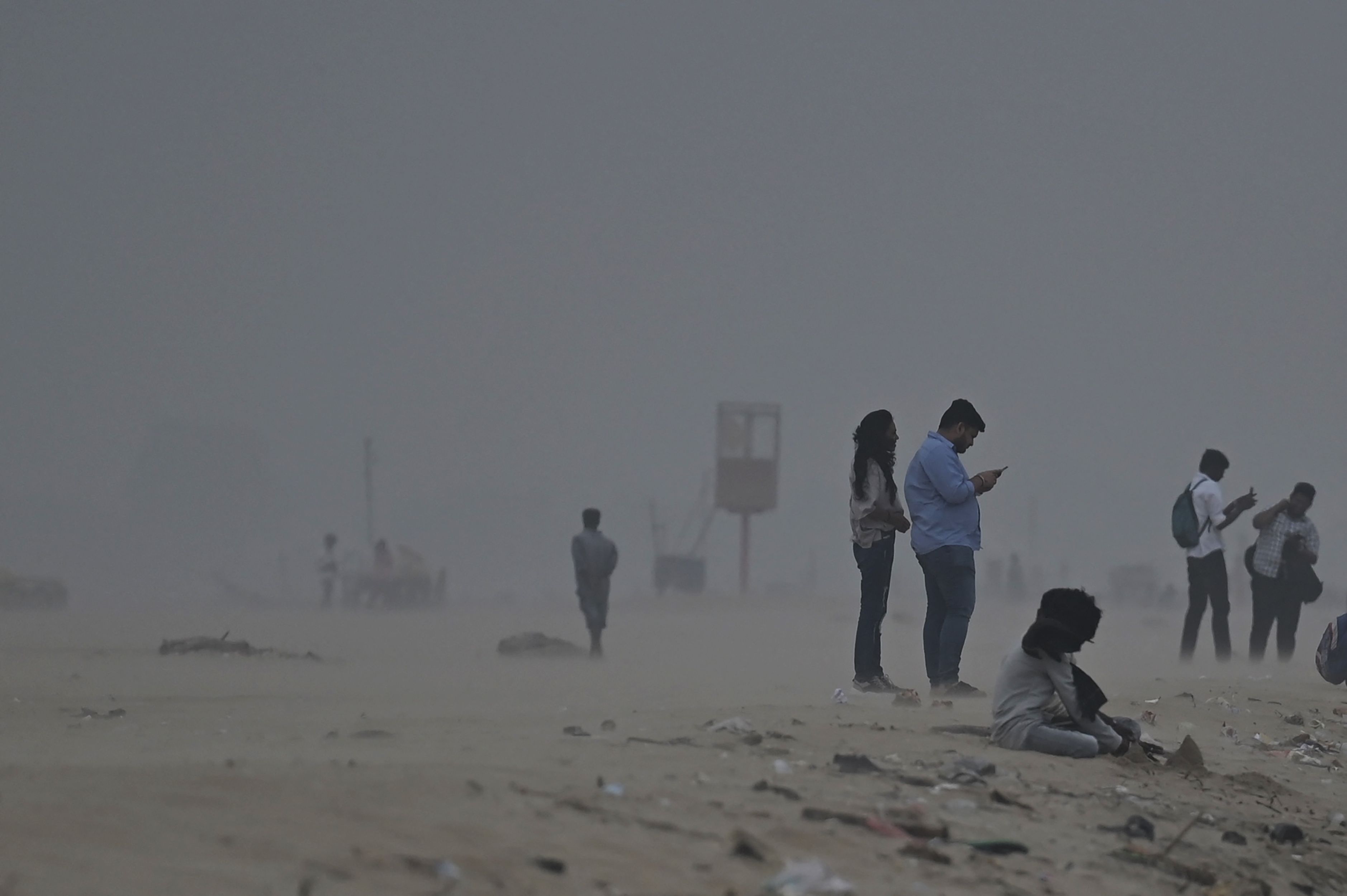 Cyclone Mandous: People walk amid heavy winds at Marina beach in Chennai. (AFP)