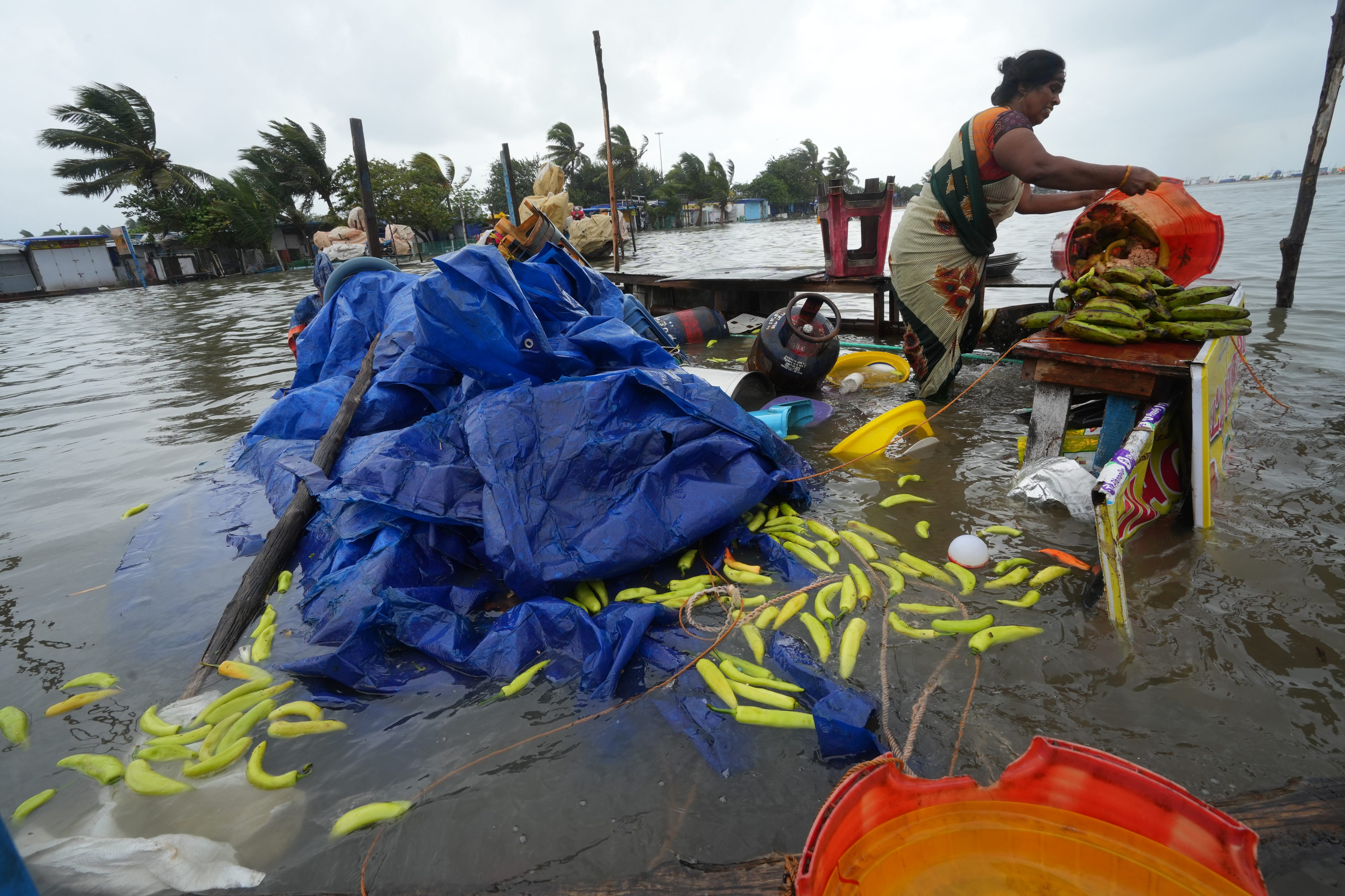 Cyclone Mandaus: A woman salvages her shop at the Marina beach following the landfall of Cyclone Mandous, in Chennai. (PTI)