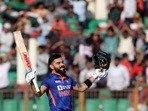 India's Virat Kohli raises his bat and helmet to celebrate scoring a century 