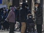 A woman sits on a foldable chair as she and residents wait in line to enter the fever clinic of a hospital in Beijing, on Sunday. (AP)