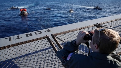 A Sasquatch Team member watches as NASA's Orion capsule makes its way towards the U.S.S. Portland (LPD 27) after being successfully secured by a NASA and US Navy team, off the coast of Baja California, Mexico, on December 11. With a return speed of 25,000 mph (40,000 kph) — considerably faster than coming in from low-Earth orbit — the capsule used a new, advanced heat shield never tested before in spaceflight. (Caroline Brehman / REUTERS) A Sasquatch Team member watches as NASA's Orion capsule makes its way towards the U.S.S. Portland (LPD 27) after being successfully secured by a NASA and US Navy team, off the coast of Baja California, Mexico, on December 11. With a return speed of 25,000 mph (40,000 kph) — considerably faster than coming in from low-Earth orbit — the capsule used a new, advanced heat shield never tested before in spaceflight. (Caroline Brehman / REUTERS)