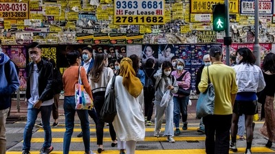 Pedestrians cross a road in front of a vacant shop in Hong Kong on December 9, 2022. (Photo by ISAAC LAWRENCE / AFP) (AFP) Pedestrians cross a road in front of a vacant shop in Hong Kong on December 9, 2022. (Photo by ISAAC LAWRENCE / AFP) (AFP)