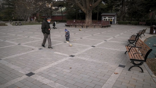 Beijing Air Pollution: A man wearing a face mask plays a ball with a child at an area used to be crowded with residents at a public park in Beijing. (AP)