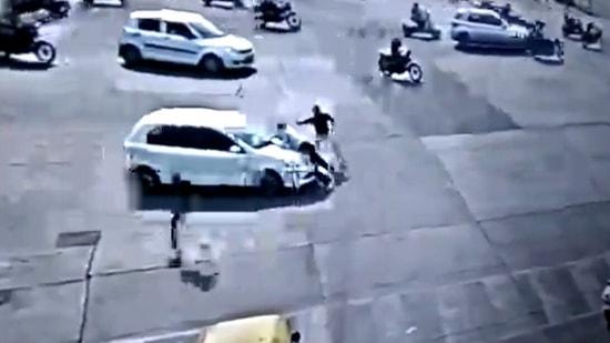A traffic policeman was seen being carried by a driver on top of his car bonnet. A traffic policeman was seen being carried by a driver on top of his car bonnet.