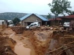 A  man walks past a car, stucked in the mud after heavy rains caused floods and landslides, on the outskirts of Kinshasa, Democratic Republic of Congo.