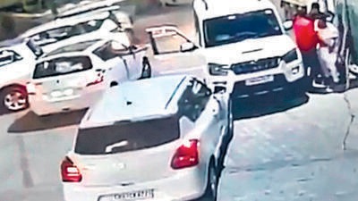 A CCTV grab of the accused opening fire at the trader, who managed to hide behind his SUV (right). (HT) A CCTV grab of the accused opening fire at the trader, who managed to hide behind his SUV (right). (HT)