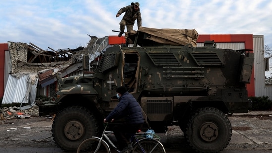 A man rides past an American MaxxPro military vehicle in the formerly Russian occupied city of Lyman, Donetsk region of Ukraine, on December 11. Fierce fighting in the region in recent weeks has left unclear which parts of Donetsk are under Russian and Ukrainian control, Reuters reported.(Shannon Stapleton / REUTERS)