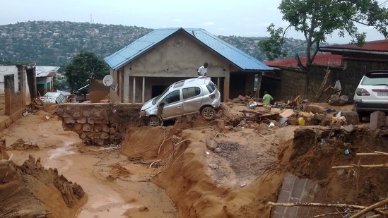 Congo Floods: A man walks past a car, stucked in the mud after heavy rains caused floods.(Reuters)