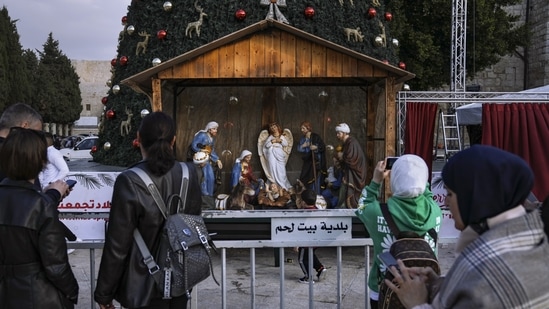 People take pictures of the Christmas tree and nativity scene in Manger Square, outside to the Church of the Nativity.(AP)