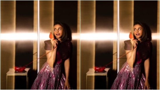 Rakul Preet earlier decked up for a photoshoot in a dark pink gown featuring dramatic short sleeves and a skirt detail striped in multiple shades of pink, black and silver.(Instagram/@rakulpreet)