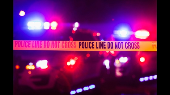 Accident or crime scene cordon tape, police line do not cross. It is nighttime, emergency lights of police cars flashing blue, red and white in the background (Getty Images/iStockphoto)