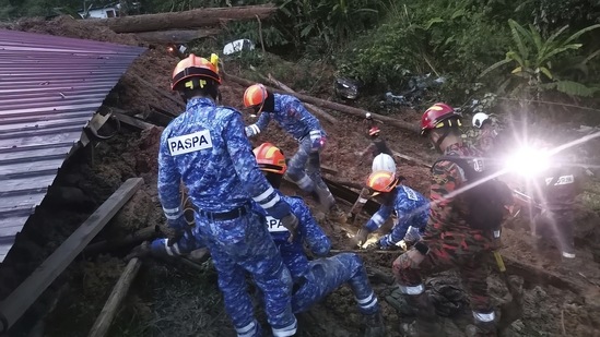 Civil Defense personnel search for survivors buried after a landslide hit a campsite in Batang Kali, Malaysia, Friday. (AP)