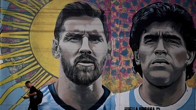 A man passes by a mural depicting Argentine football stars Lionel Messi (L) and late Diego Maradona (R) in the eve of Qatar 2022 World Cup final football match between Argentina and France in Buenos Aires, on December 16, 2022. (Photo by Luis ROBAYO / AFP) (AFP) A man passes by a mural depicting Argentine football stars Lionel Messi (L) and late Diego Maradona (R) in the eve of Qatar 2022 World Cup final football match between Argentina and France in Buenos Aires, on December 16, 2022. (Photo by Luis ROBAYO / AFP) (AFP)