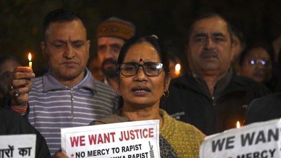 Asha Devi (C), mother of the 2012 Delhi gang rape victim, along with people hold candles and placards during a vigil on the tenth anniversary of the heinous gang rape of a young woman in Delhi on December 16.(AFP)