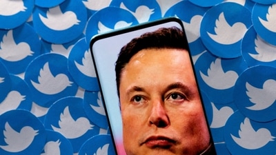 An image of Elon Musk is seen on a smartphone placed on printed Twitter logos in this picture illustration. (REUTERS)