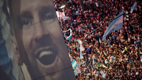 Argentina fans celebrate winning the World Cup at the Obelisk on Sunday, December 18, with an image of the captain Lionel Messi. Fireworks cracked, car horns sounded and fans draped in the national blue and white colors sang, danced, and waved flags. &nbsp;(Agustin Marcarian / REUTERS)