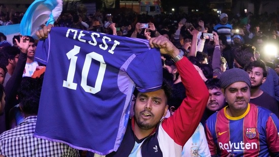 An Argentina supporter from Kolkata celebrates the FIFA World Cup win holding a replica national team jersey bearing the name of Lionel Messi, the captain.(AP)