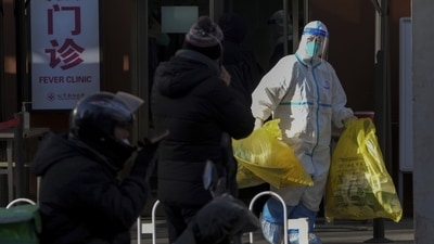 A medical worker in protective gear carries bags of medical waste from a fever clinic in Beijing, on December 19. Beijing health officials Tuesday said that only those who had directly died of respiratory failure caused by the virus would be counted under Covid death statistics, Reuters reported. (Andy Wong / AP) A medical worker in protective gear carries bags of medical waste from a fever clinic in Beijing, on December 19. Beijing health officials Tuesday said that only those who had directly died of respiratory failure caused by the virus would be counted under Covid death statistics, Reuters reported. (Andy Wong / AP)