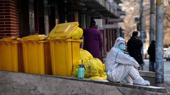 A worker wearing personal protective equipment (PPE) sits next to waste material outside a fever clinic amid the Covid-19 pandemic in Beijing on December 19.(Noel Celis / AFP)