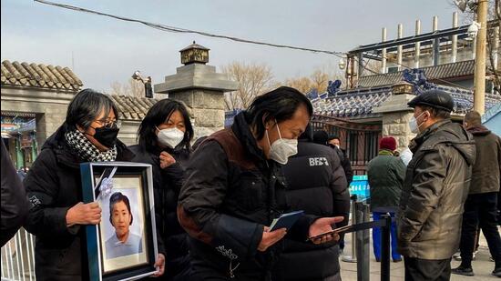 People carry a picture frame of a loved one outside a crematorium in Beijing on Tuesday. Workers at crematoriums in the capital city say they are overwhelmed as China faces a Covid surge. (AFP)