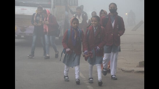 School students brave heavy fog, the first for this winter, as they head towards their school in Prayagraj on Tuesday morning. (HT)