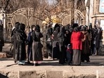 Afghan female university students stop by Taliban security personnel stand next to a university in Kabul. 