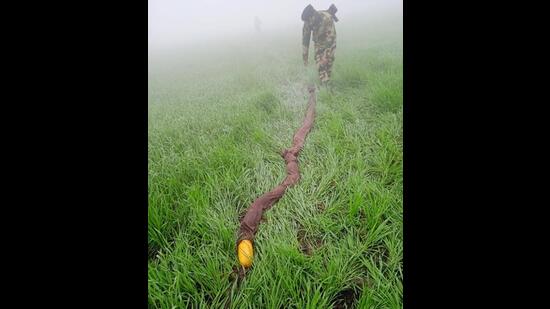 A Border Security Force (BSF) man recovering packets of contraband suspected to be heroin near the India-Pakistan border in Fazilka district of Punjab on Wednesday. (HT Photo)