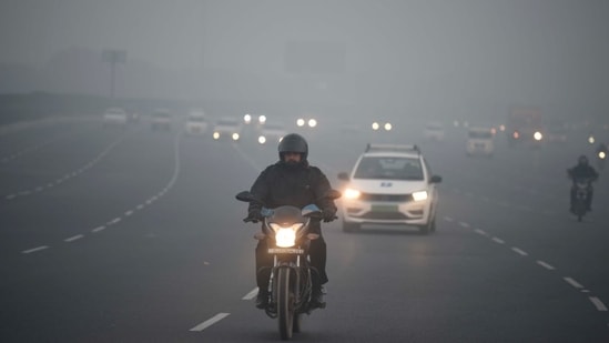 Vehicles move slowly amid low visibility due to fog on a cold winter morning. (Parveen Kumar/HT Photo)