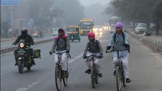 School children ride cycles on a cold and foggy morning in New Delhi on Wednesday. (PTI)