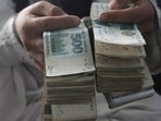 A man holds Pakistani currency bundles.(AP) A man holds Pakistani currency bundles.(AP)