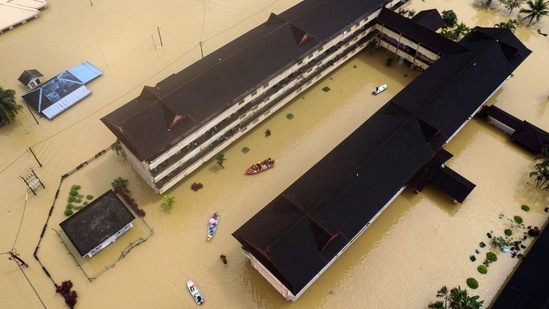 Residents are rescued by boats from the flood relief centre after the flood water rose and partially submerged a building at Dungun, Terengganu, on December 21. A two-year-old girl was swept away by strong currents in Terengganu on December 18, amid the floods.(Reuters)